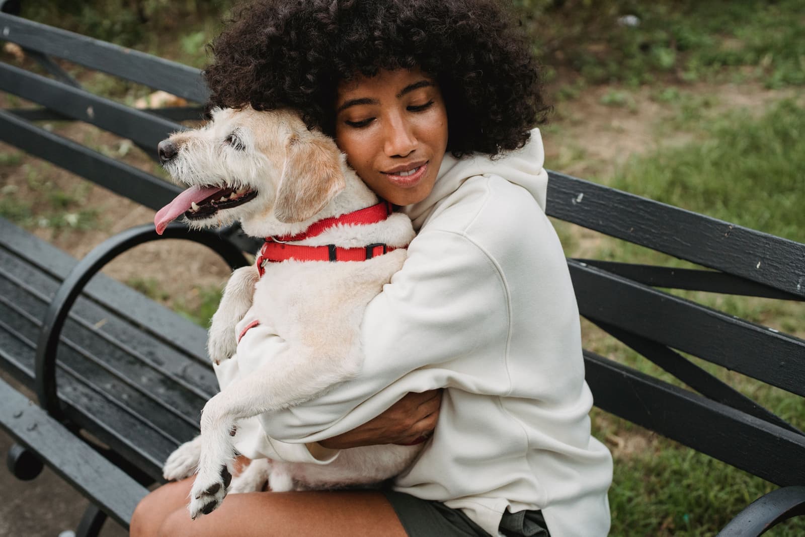 A woman hugging her dog outdoors in soft daylight
