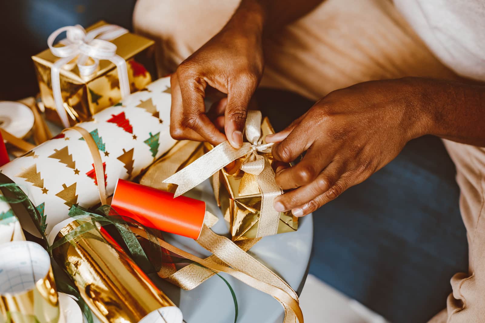 Hands wrapping a small gift on a pale, airy tabletop